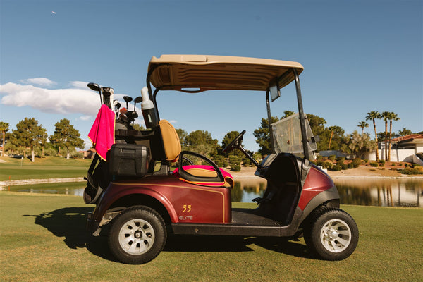 Burgundy golf cart with Grove + Green signature 100% terry cloth golf cart seat cover in hot pink with orange trim.